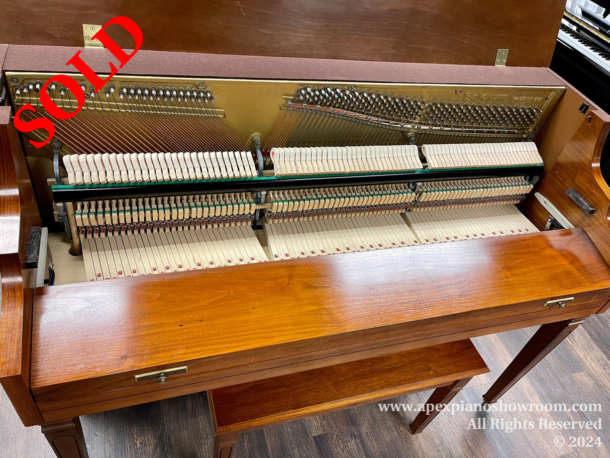 Interior mechanics of an open upright piano showcasing the hammers, strings, and dampers in a showroom, with a warm wooden exterior and matching bench.