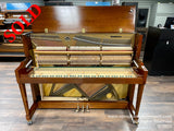 A Baldwin upright piano with its front panel open, revealing the intricate internal mechanism of hammers and strings, placed on a showroom floor.