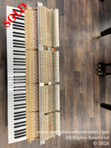 Disassembled piano action on display with corresponding keys laid out on a wooden floor, illustrating the internal mechanism of a piano and the intricate relationship between keys and hammers.