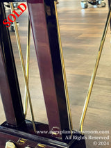 Close-up view of a high-gloss black piano leg with brass casters on a hardwood floor, indicating the elegant design details of a grand piano.