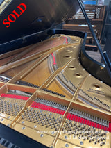 Interior view of a Baldwin grand piano showing strings, hammers, and the soundboard with the brand name clear, reflective of piano craftsmanship and quality within an indoor setting.