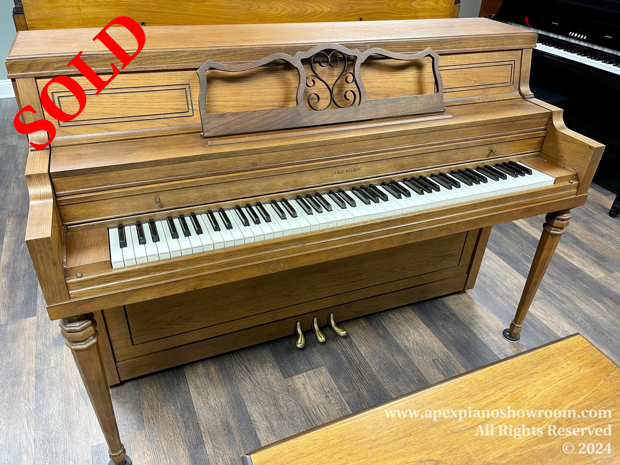 A classic upright piano with a polished wooden finish and decorative music stand — 88 keys displayed on a fully intact keyboard — ornate wooden legs supporting the instrument's structure.