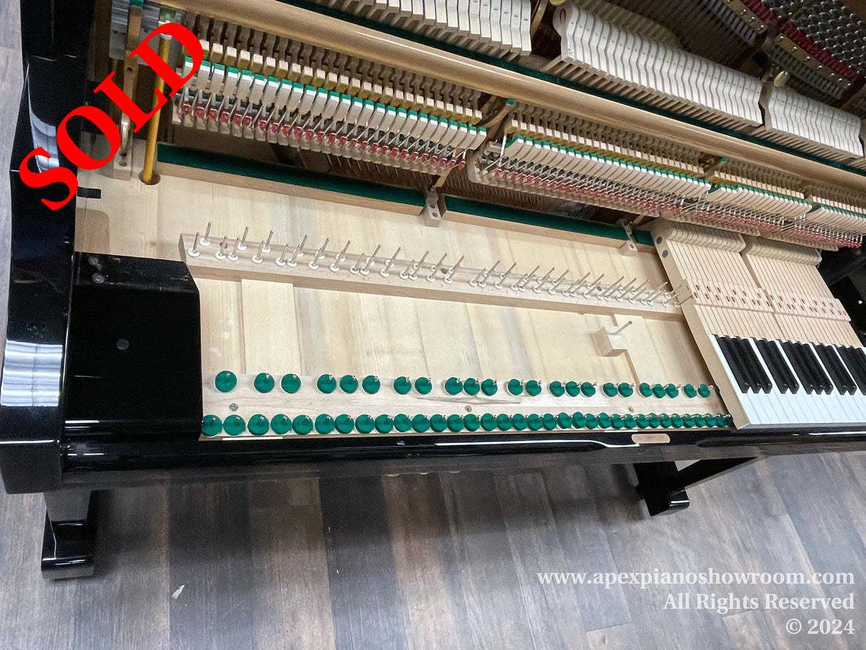 Interior of a grand piano showing strings, hammers, and dampers, with the keyboard partly visible on the right side.