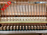 Interior view of a piano showing strings, tuning pins, and hammers, indicative of piano craftsmanship and internal mechanisms used for creating music.