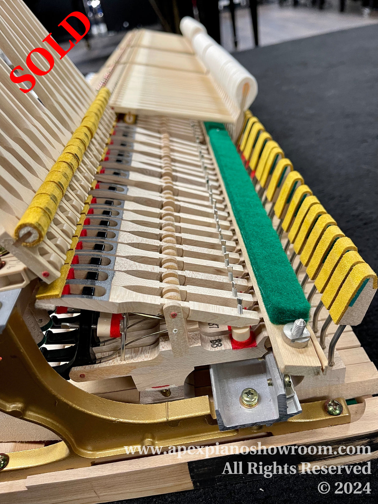 Close-up view of the interior mechanism of a grand piano, showcasing the hammers, dampers, and strings with a clear focus on the intricate craftsmanship and wooden components.