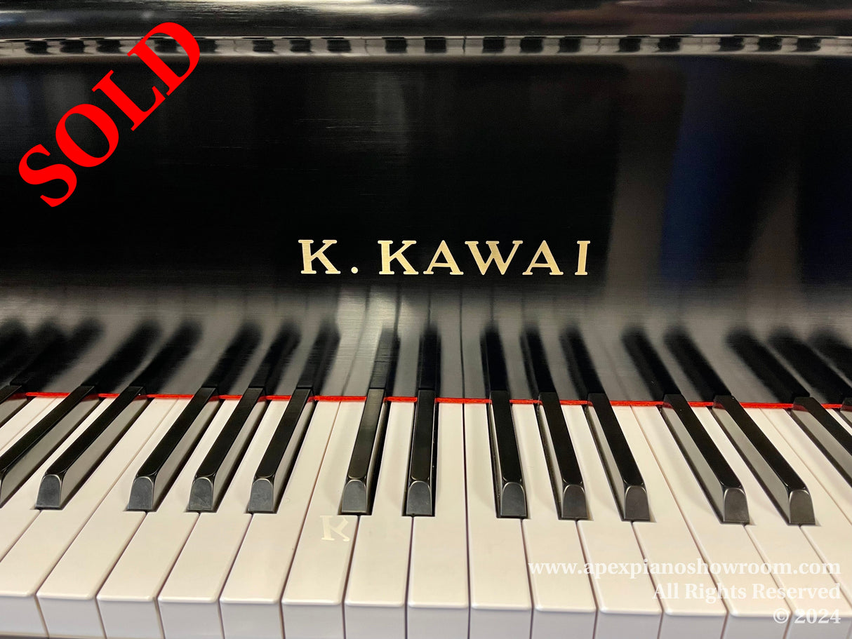 A Kawai piano with black and white keys prominently displayed and the manufacturer's name, K. KAWAI, visible above the keyboard.