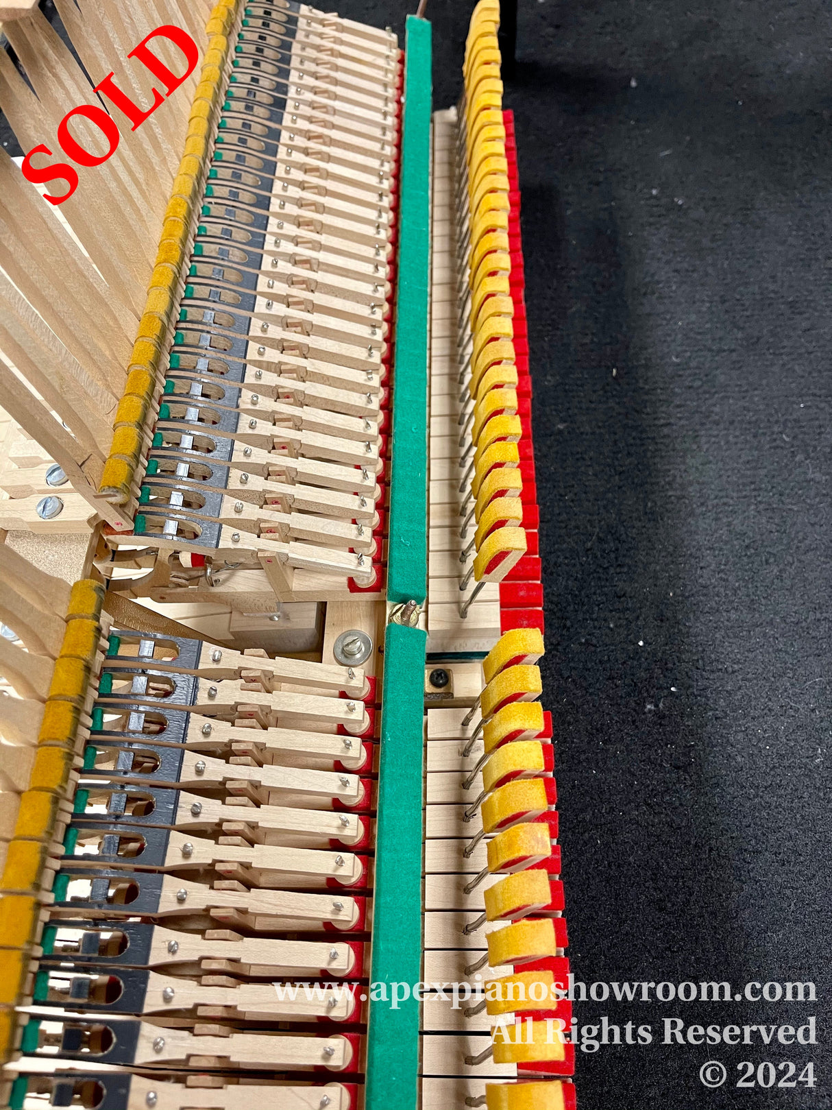 Interior view of a piano showcasing the hammer mechanism and strings, with dampers and hammers visible, indicative of piano maintenance or tuning process.