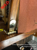 Close-up view of a pianos brass hardware, including the hinges and locks, against a wooden finish and red interior felt lining.