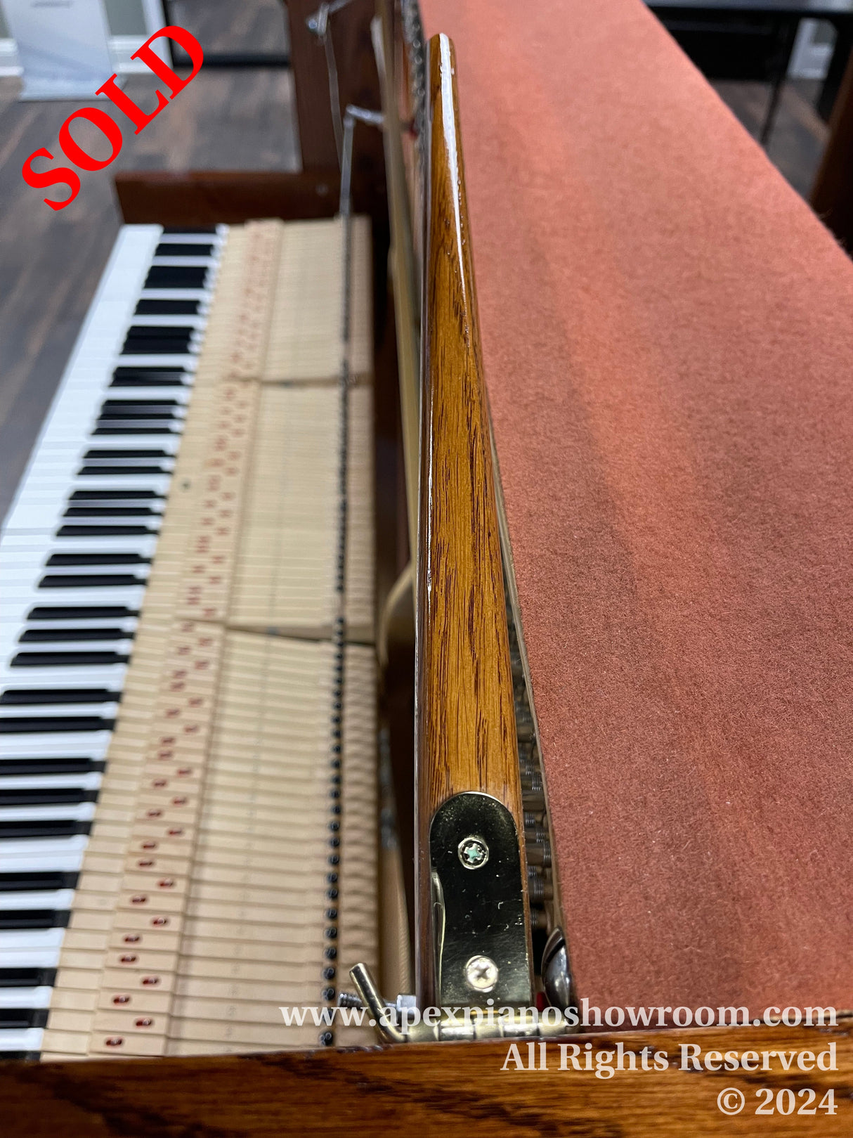 Close-up view of a pianos keys and internal hammer mechanism, showcasing the wooden texture, intricate design, and string alignment typical of classic acoustic pianos.