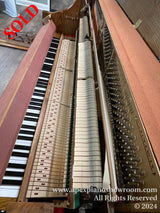 Interior view of an open grand piano showing the keys, hammers, and strings with a focus on the intricate parts and mechanisms used for producing sound.