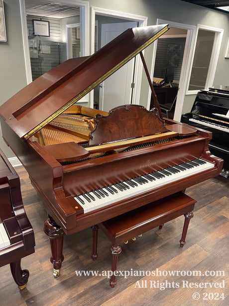 Elegant grand piano with polished mahogany finish, ornate music desk and sturdy carved legs, displayed in a showroom setting — model by Story & Clark, lid propped open to reveal strings and interior mechanics.