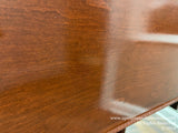 Close-up of a wooden piano finish with light reflecting off its polished surface showcasing the woods grain texture and sheen, indicative of careful craftsmanship in piano casework.