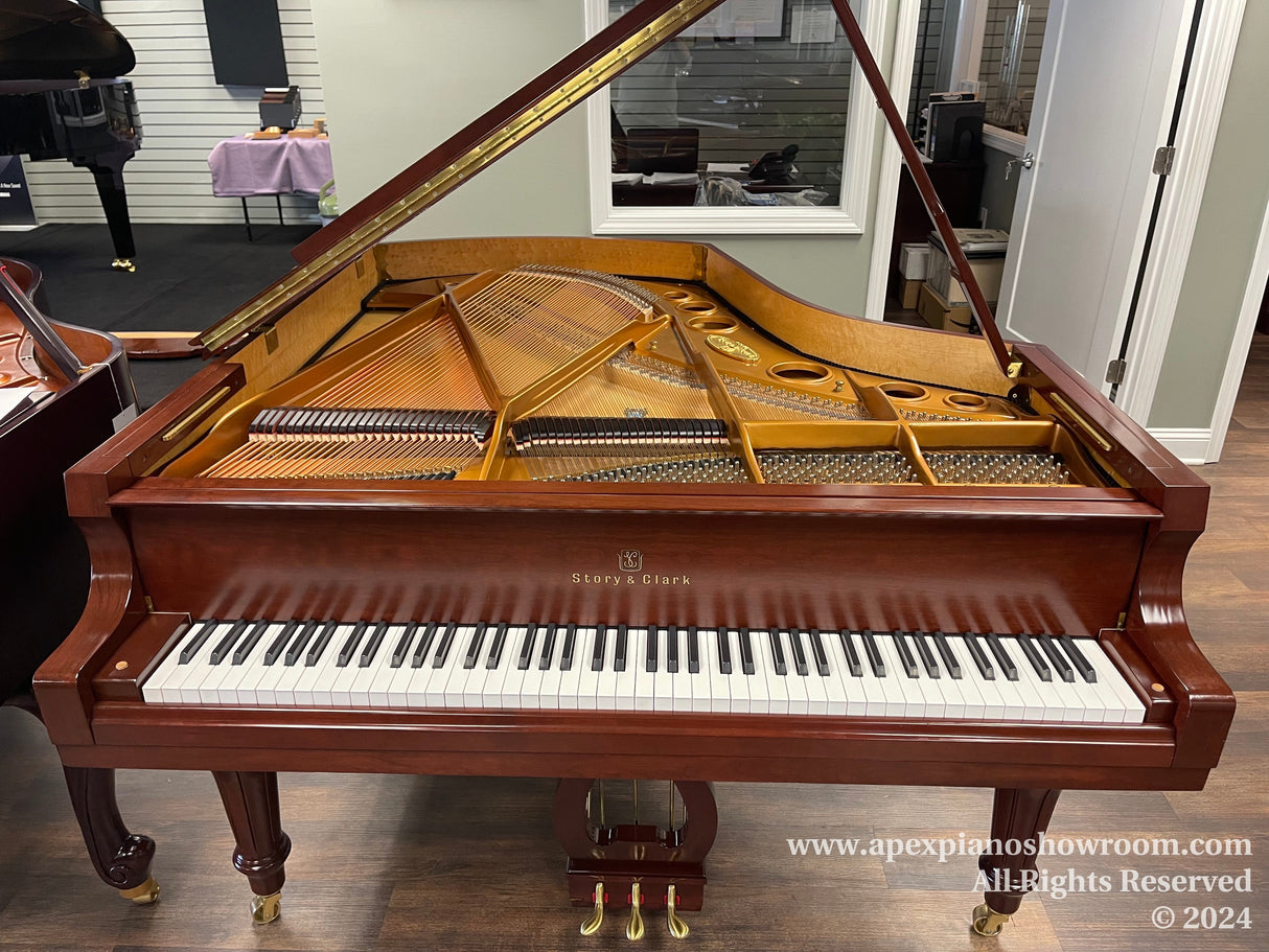 A Story & Clark grand piano with open lid, showing its strings and hammers, placed on a showroom floor with wooden flooring and light walls, reflecting a tasteful environment for presenting quality pianos.