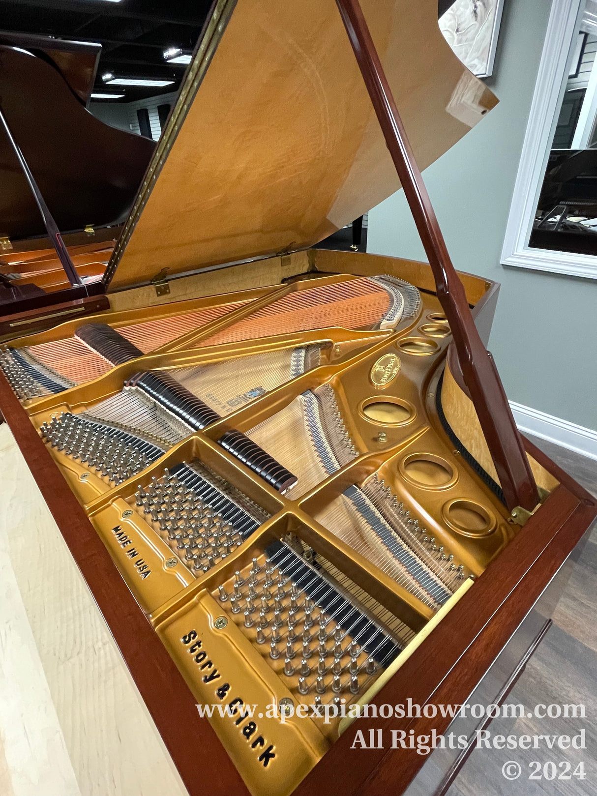 Interior view of a grand piano showing open lid, golden frame, and strings, with a logo of Steinway & Sons and text Made in USA visible.