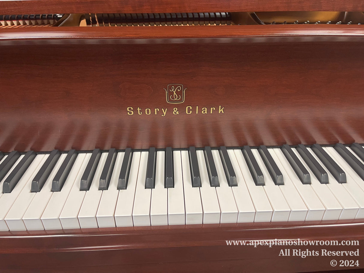 Close-up view of a Story & Clark piano keyboard with glossy mahogany finish and the brand logo visible above the keys.