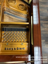 Interior view of a Story & Clark upright piano showing the strings, hammers, and tuning pins with branding visible. The pianos wooden structure and polished finish are also prominently displayed.