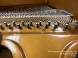 Close-up view of a grand pianos interior showcasing the strings, tuning pins, and copper wound bass strings, all indicative of quality craftsmanship in piano construction.