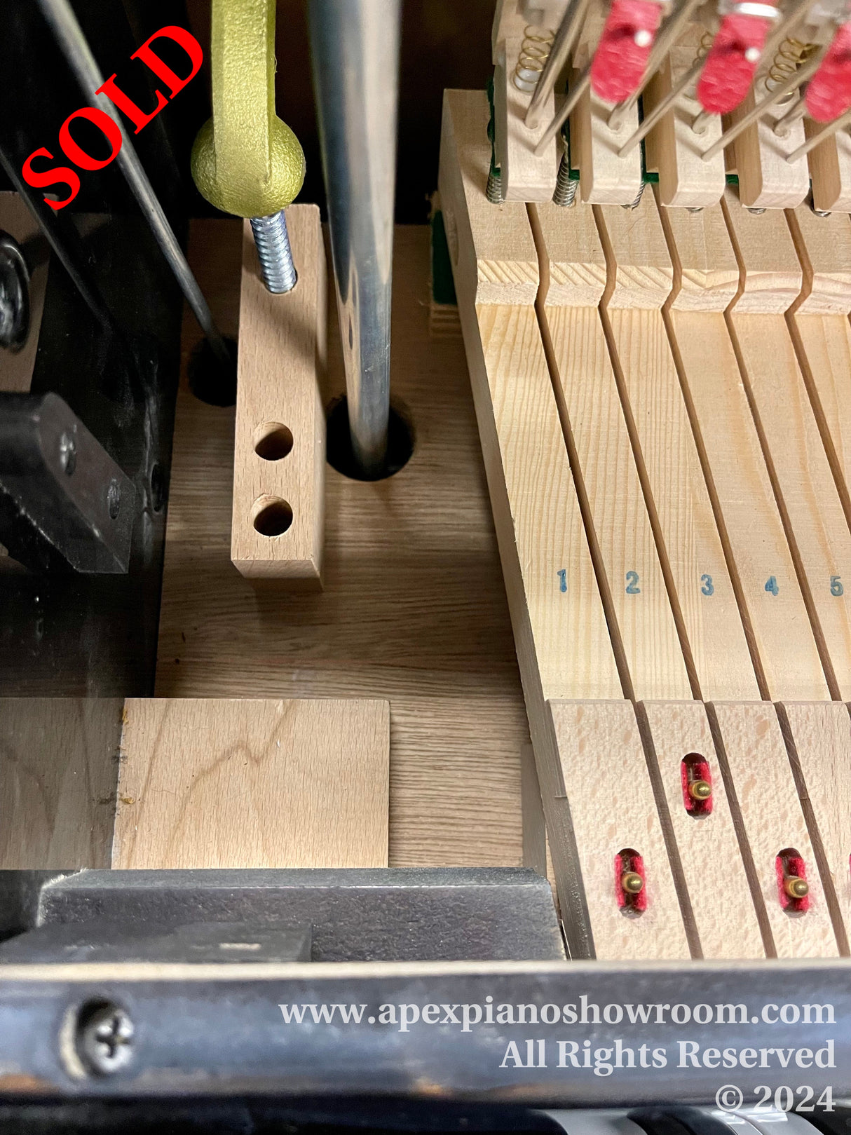 Close-up view of a piano action mechanism, displaying hammers, dampers, and strings typically found inside a grand piano, with a focus on the intricate parts and felts that contribute to the instruments tonal quality.