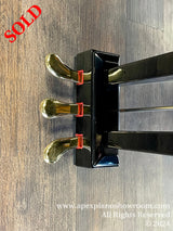 A close-up view of the polished brass casters and sleek black legs of a grand piano on a wooden floor.