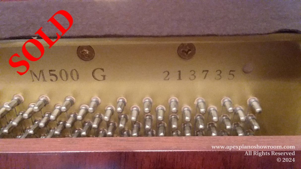Close-up of a pianos serial number and tuning pins indicating the model M500 G and serial number 2137355 inside a pianos upper cabinet, above the pinblock.