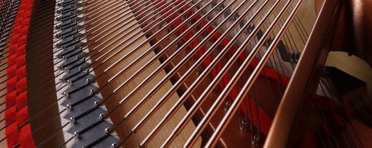 Close-up view of the internal strings and dampers inside a grand piano, showcasing the intricate mechanism of a piano's sound production.