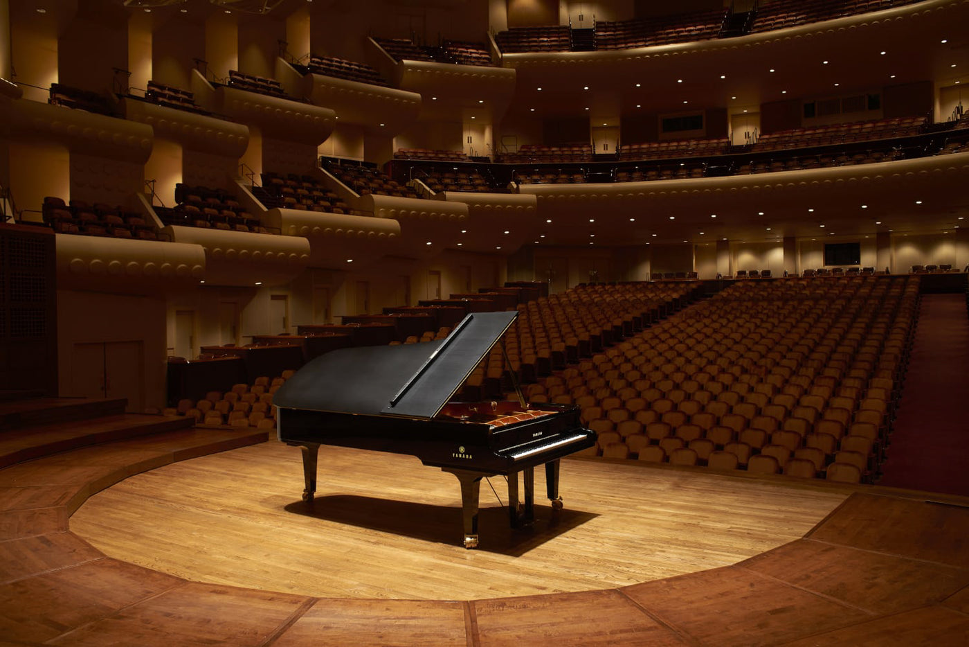 Grand piano centered on the stage of an elegant concert hall, anticipating a performance, with empty seats gently lit, highlighting the potential for a musical event.