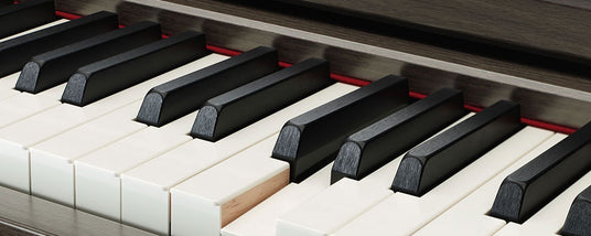 Close-up of piano keys showing both black and white keys with a section of wood grain on the piano visible.