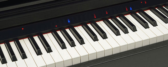 Close-up of piano keys with red and blue lights indicating notes on a digital piano.