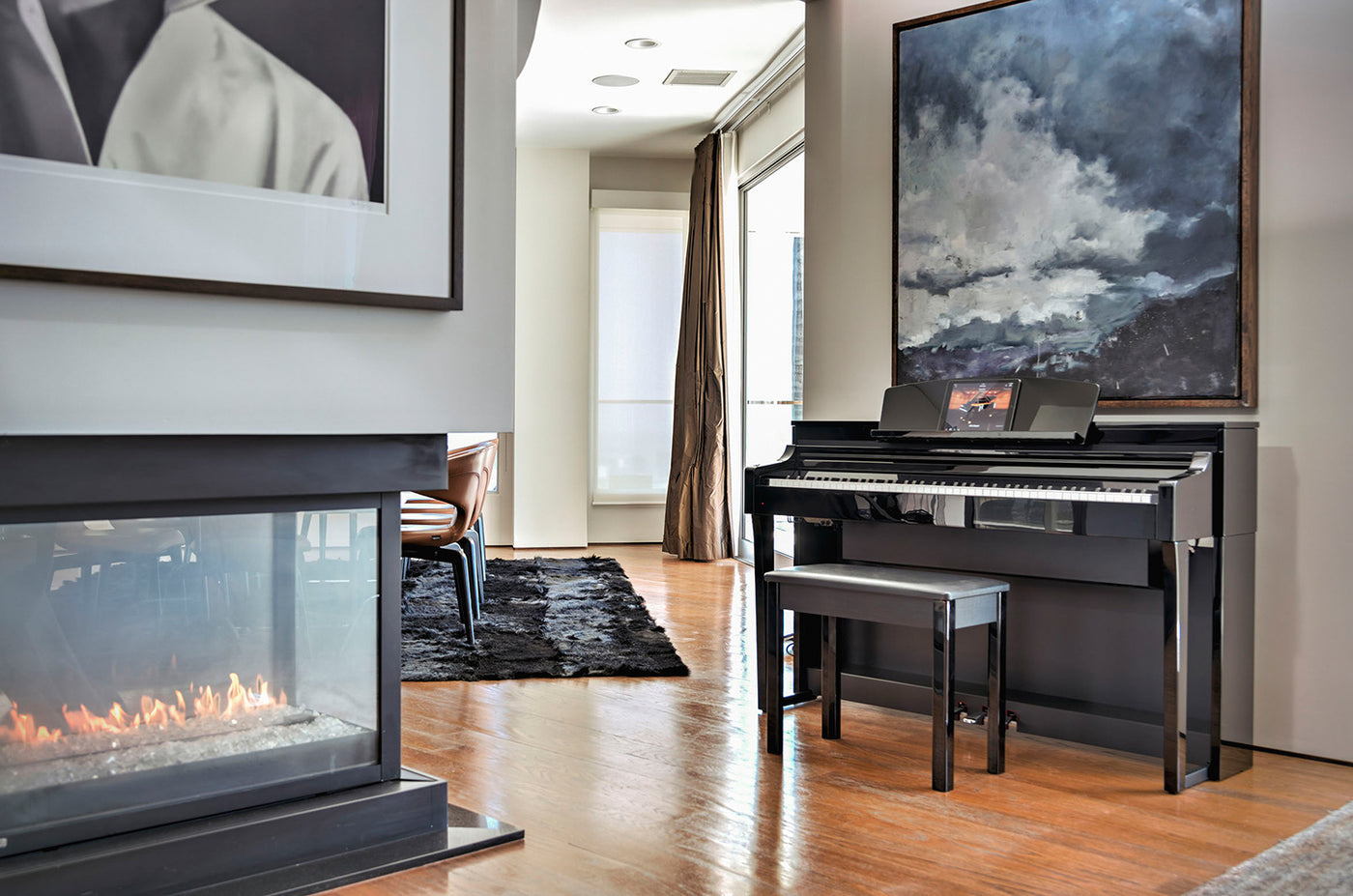 Modern digital piano placed in a well-decorated living room with a fireplace, hardwood floor, and large abstract art piece, illustrating a sophisticated setting for music enthusiasts.