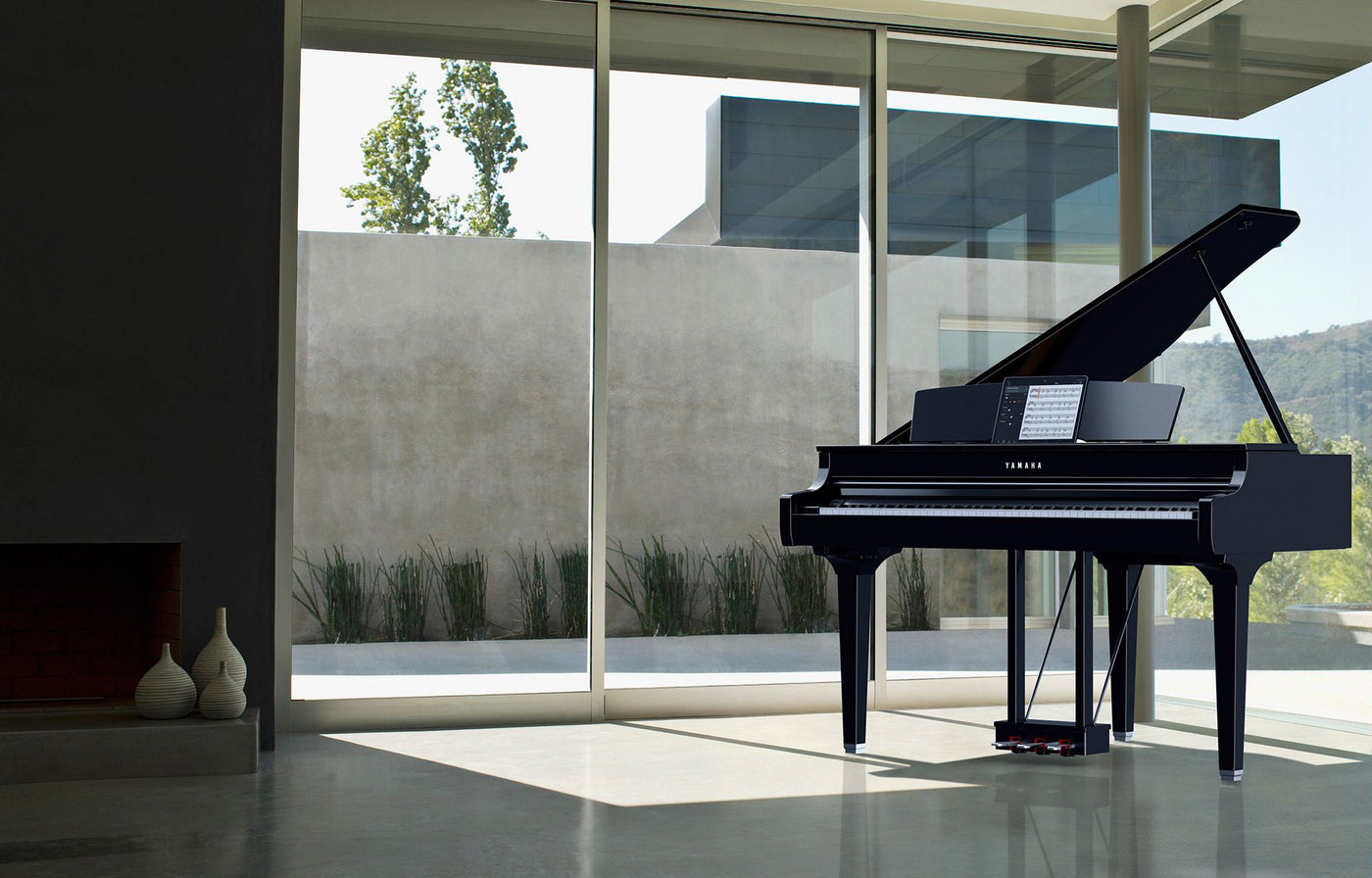A sleek black grand piano by Yamaha positioned in a modern, sunlit room with floor-to-ceiling windows overlooking a serene landscape, highlighting the elegance and contemporary design suitable for a refined musical setting.