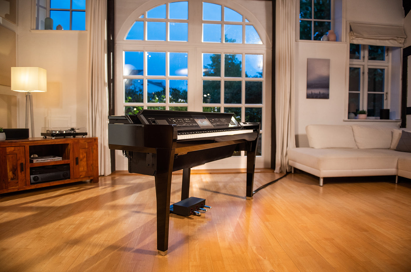 Elegant digital piano positioned in a well-lit living room with large windows and hardwood flooring, showcasing a modern interior design that integrates musical instruments as focal points of residential spaces within the piano industry.