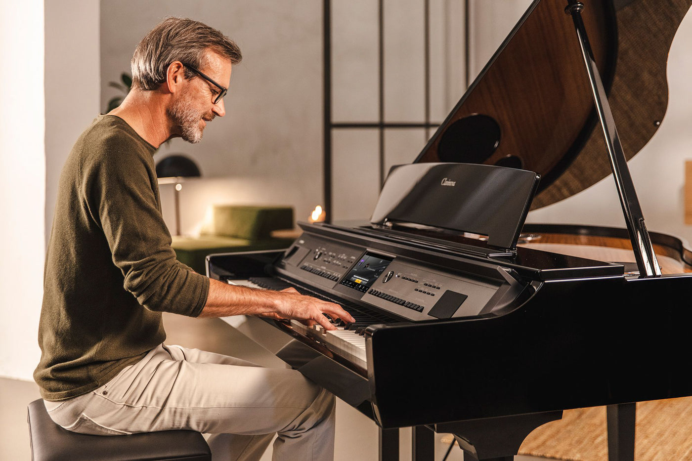 Man playing a digital grand piano in a well-lit room, reflecting a modern approach to piano design and technology.