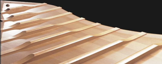 Close-up of the wooden soundboard and ribs inside a grand piano, showcasing the craftsmanship and materials used in piano construction.