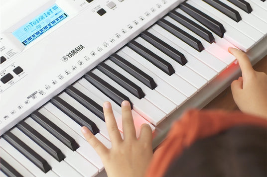 Child's hands practicing on a Yamaha digital piano keyboard, indicating early music education or beginner piano lessons.
