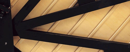 Close-up view of black piano parts contrasting with the ivory-colored interior structure, possibly representing the inside mechanism or framework of a grand piano.