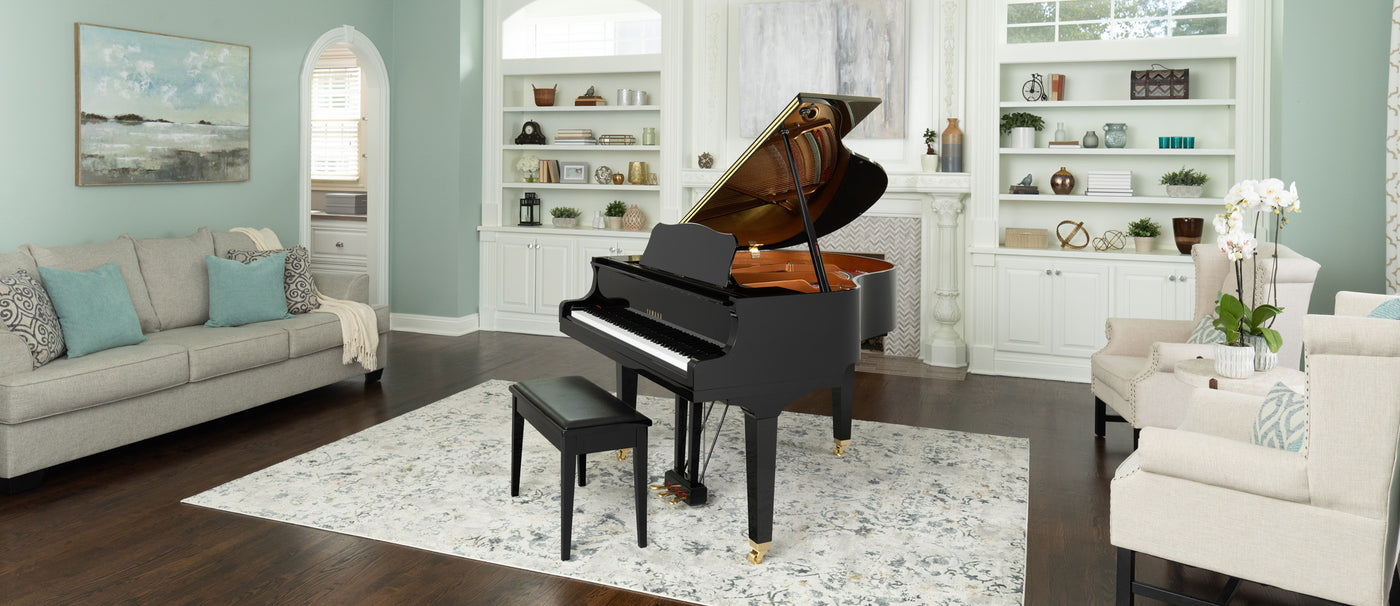 Elegant black grand piano with open lid in a bright living room setting, including a piano bench, decorative shelving, and tasteful home decor.