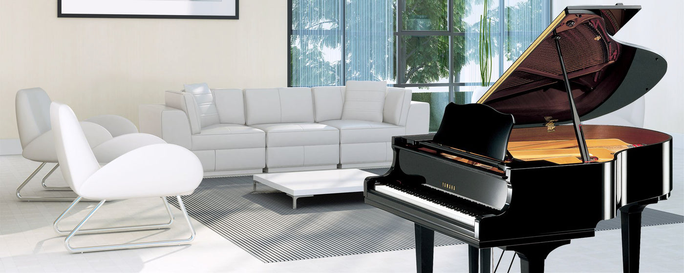 A modern living room featuring a black grand piano with an open lid, positioned next to a large window overlooking greenery, potentially indicative of a piano showroom or a musician's residence.
