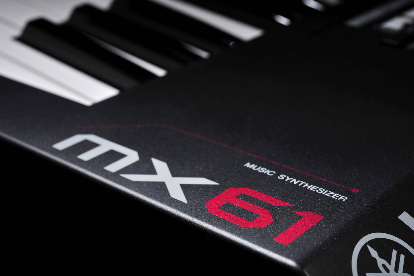 close-up of the corner of a music synthesizer keyboard showing black and white keys with the model number 'mx61' and the text 'music synthesizer' in red and white lettering.