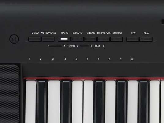 Close-up view of a digital piano's control interface, showing buttons for demo, metronome, different instrument sounds, and tempo controls above black and white keyboard keys.