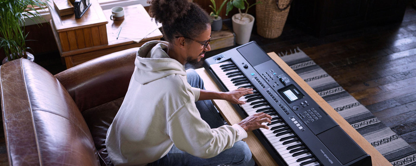 Man playing a modern digital keyboard piano in a cozy home environment.