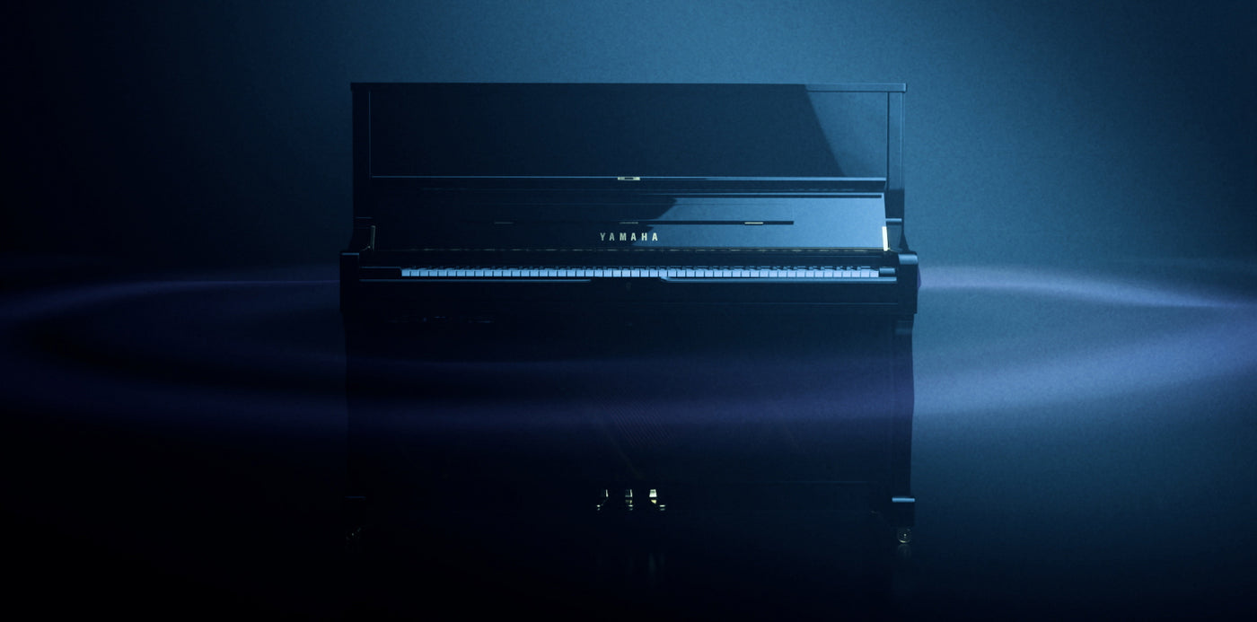 Yamaha upright piano highlighted with ambient blue lighting in a dark room, exemplifying modern piano design and elegance.