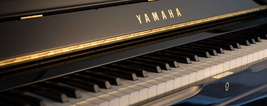 Close-up view of a Yamaha grand piano showcasing its black and white keys, with the brand name visible on the front panel.