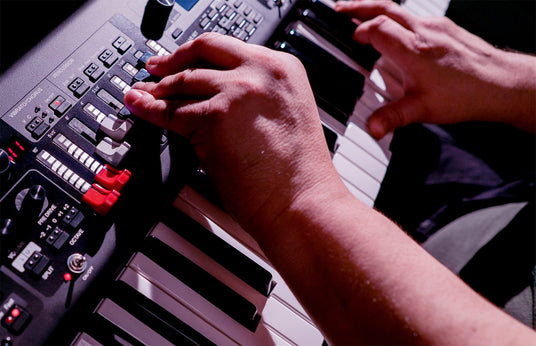 Close-up of a musician's hands adjusting controls on a digital piano during a live performance.