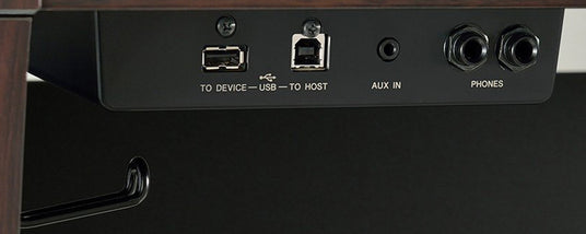 Close-up of the input/output panel on a piano with ports labeled "TO DEVICE," "USB TO HOST," "AUX IN," and "PHONES."