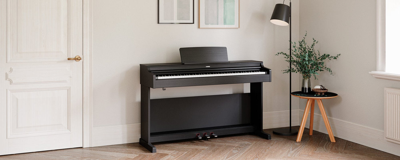An elegant black digital piano positioned in a well-lit room with minimalist decor, showcasing modern home integration of musical instruments for the contemporary pianist.
